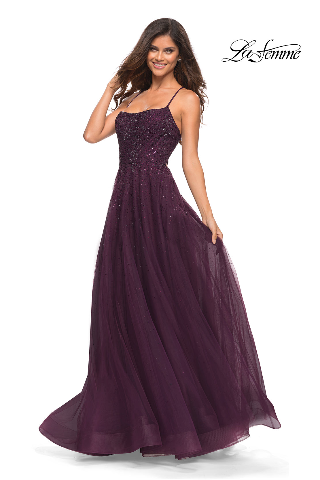 A woman poses against a white background in the Corset-Back Long La Femme A-Line Prom Dress, a sleeveless, floor-length dark purple gown featuring thin straps and a tulle skirt. The